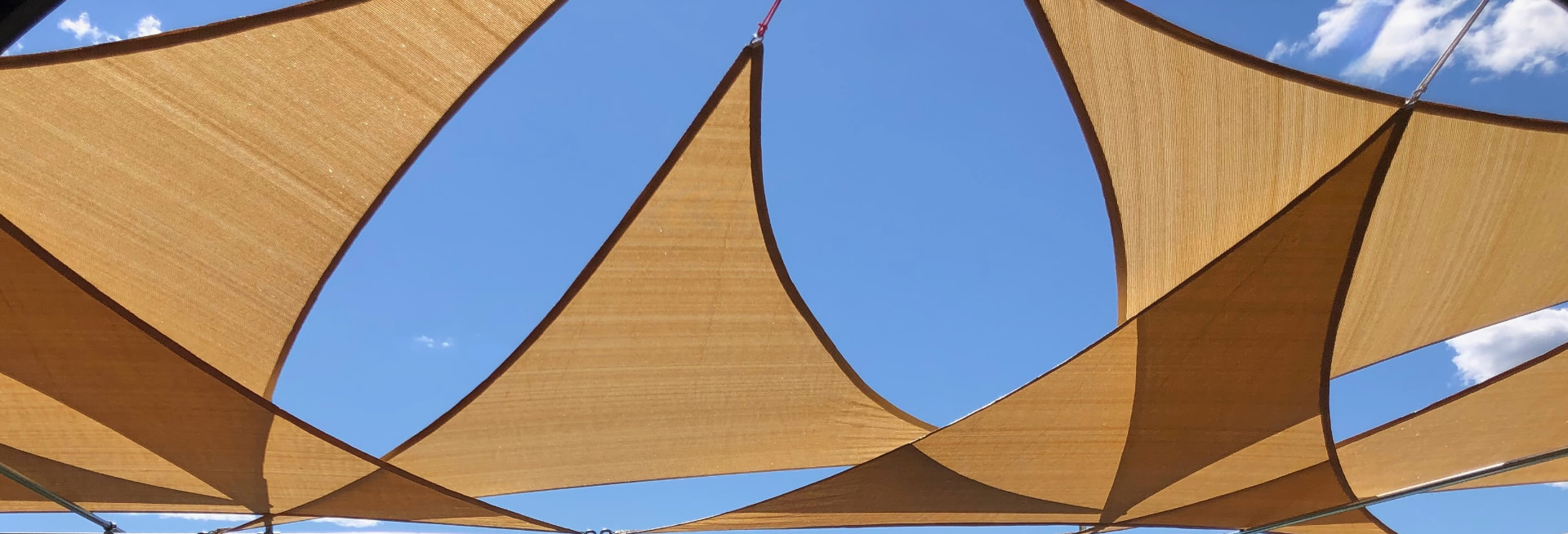 Golden tensile shade sails against a clear blue sky